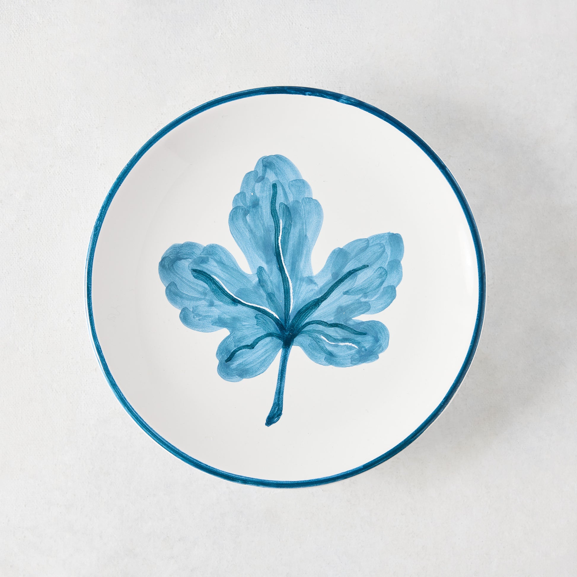 Peter Dunham + Hudson Grace hand-painted white appetizer plate with a single blue fig leaf and blue border.
