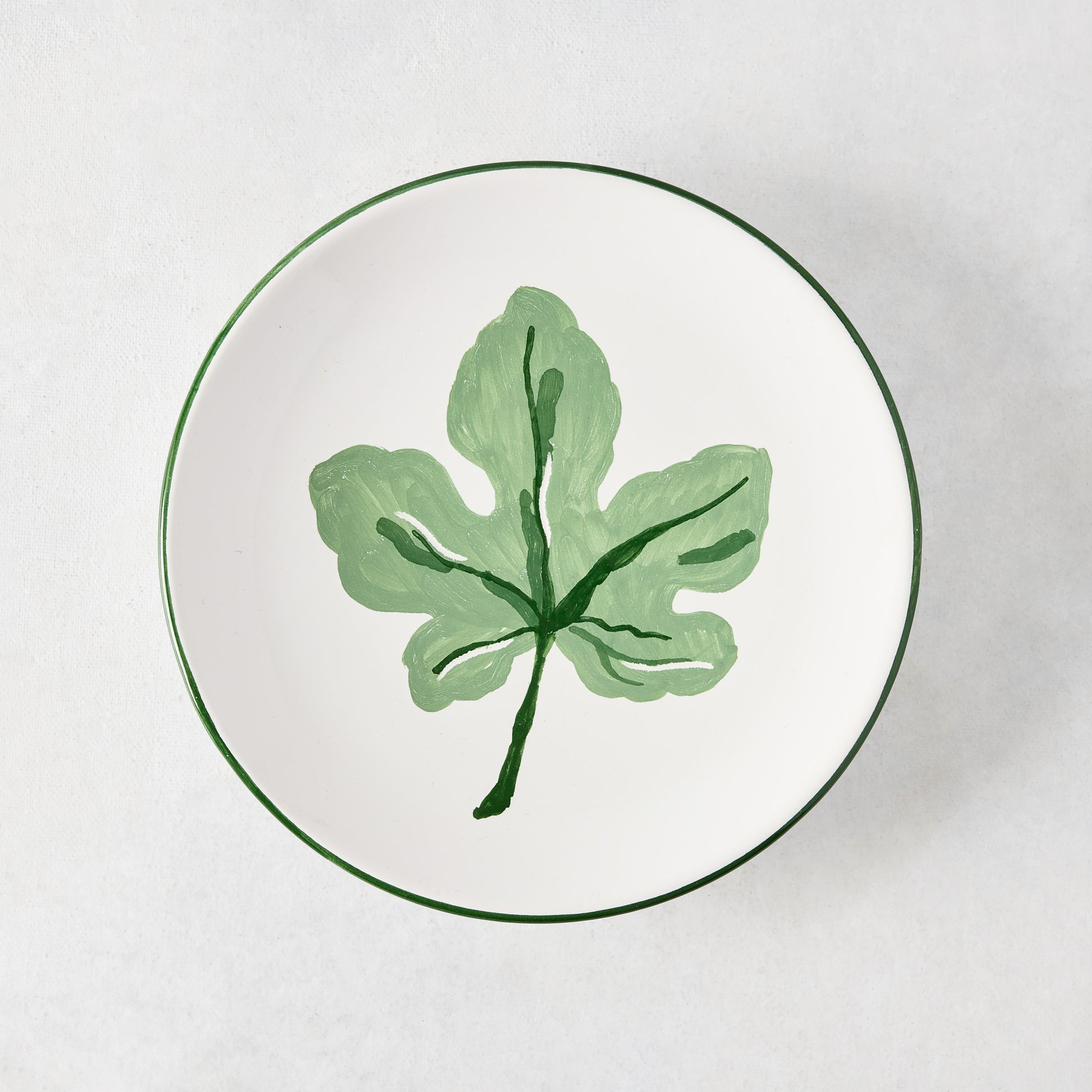 Peter Dunham + Hudson Grace hand-painted white appetizer plate with a green fig leaf and green border.