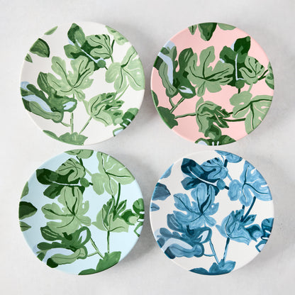 Four ceramic salad plates with hand-painted green and blue fig leaf patterns on white, pink, and light blue backgrounds.