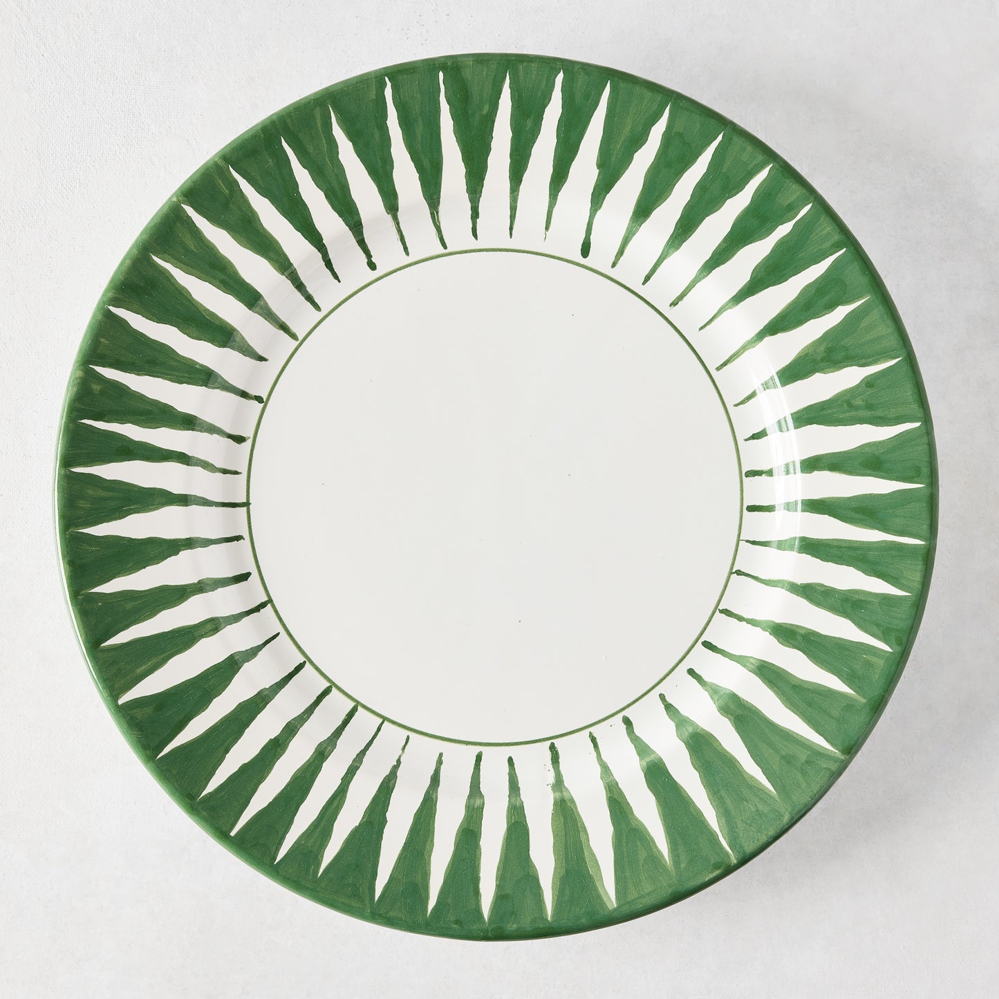 Peter Dunham + Hudson Grace hand-painted dark green sunburst dinner plate with white center.