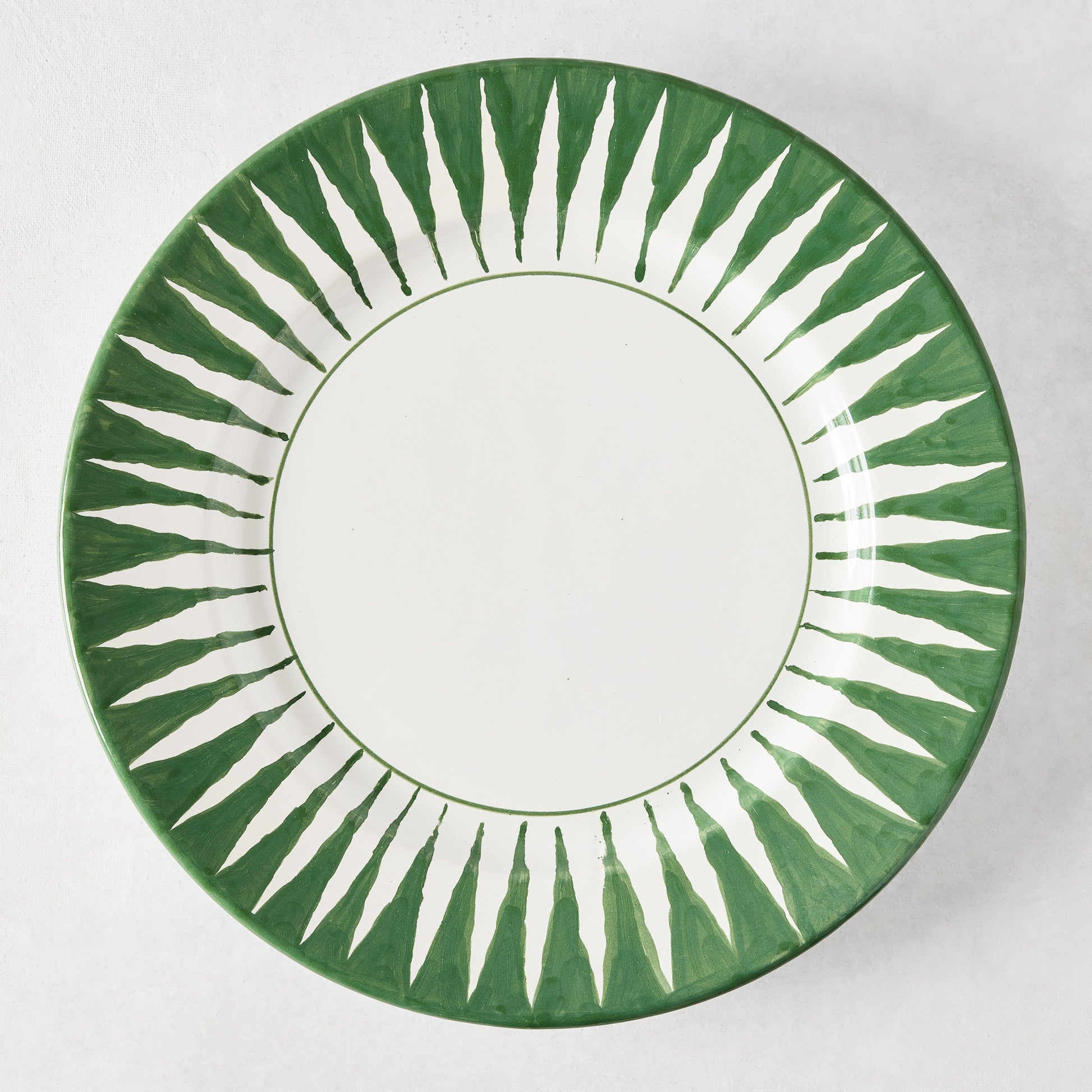 Peter Dunham + Hudson Grace hand-painted dark green sunburst dinner plate with white center.