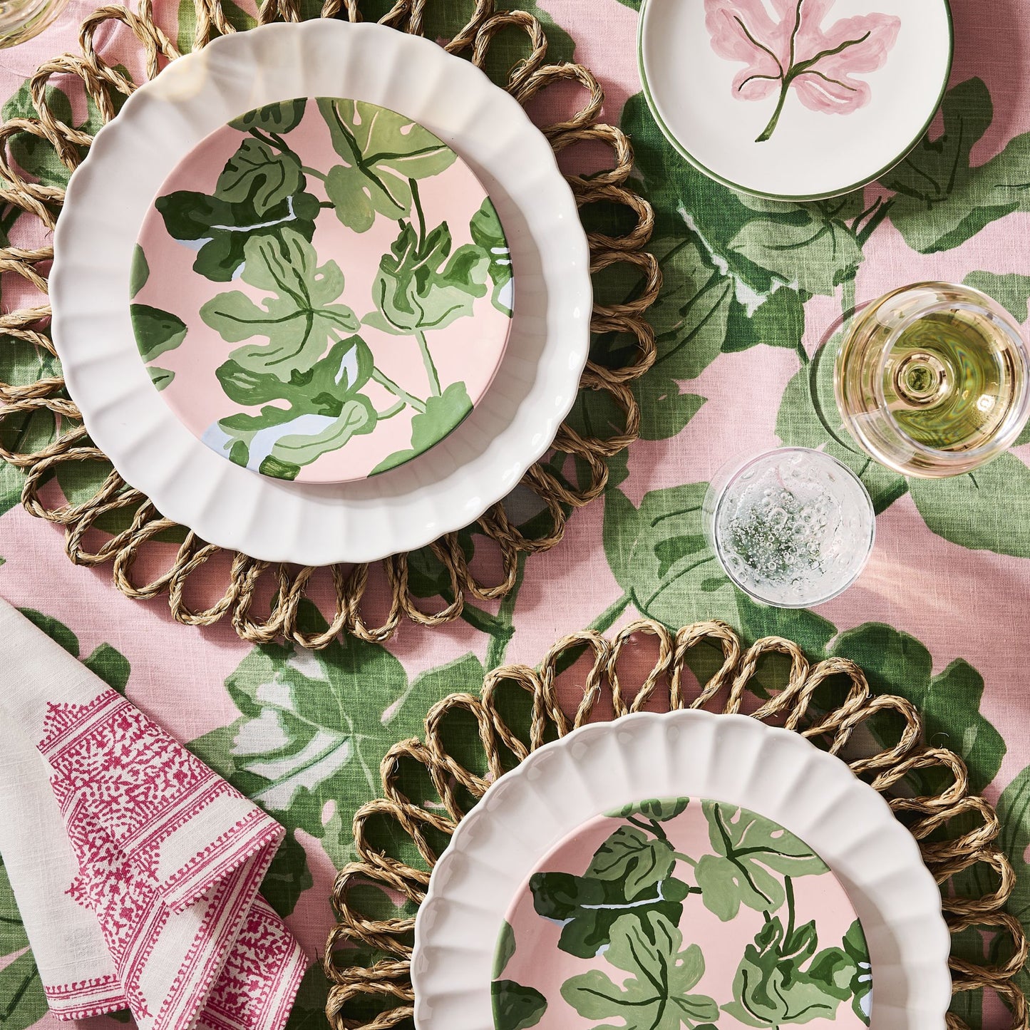 Hand-painted pink and green fig leaf appetizer plate by Peter Dunham + Hudson Grace on a woven placemat.