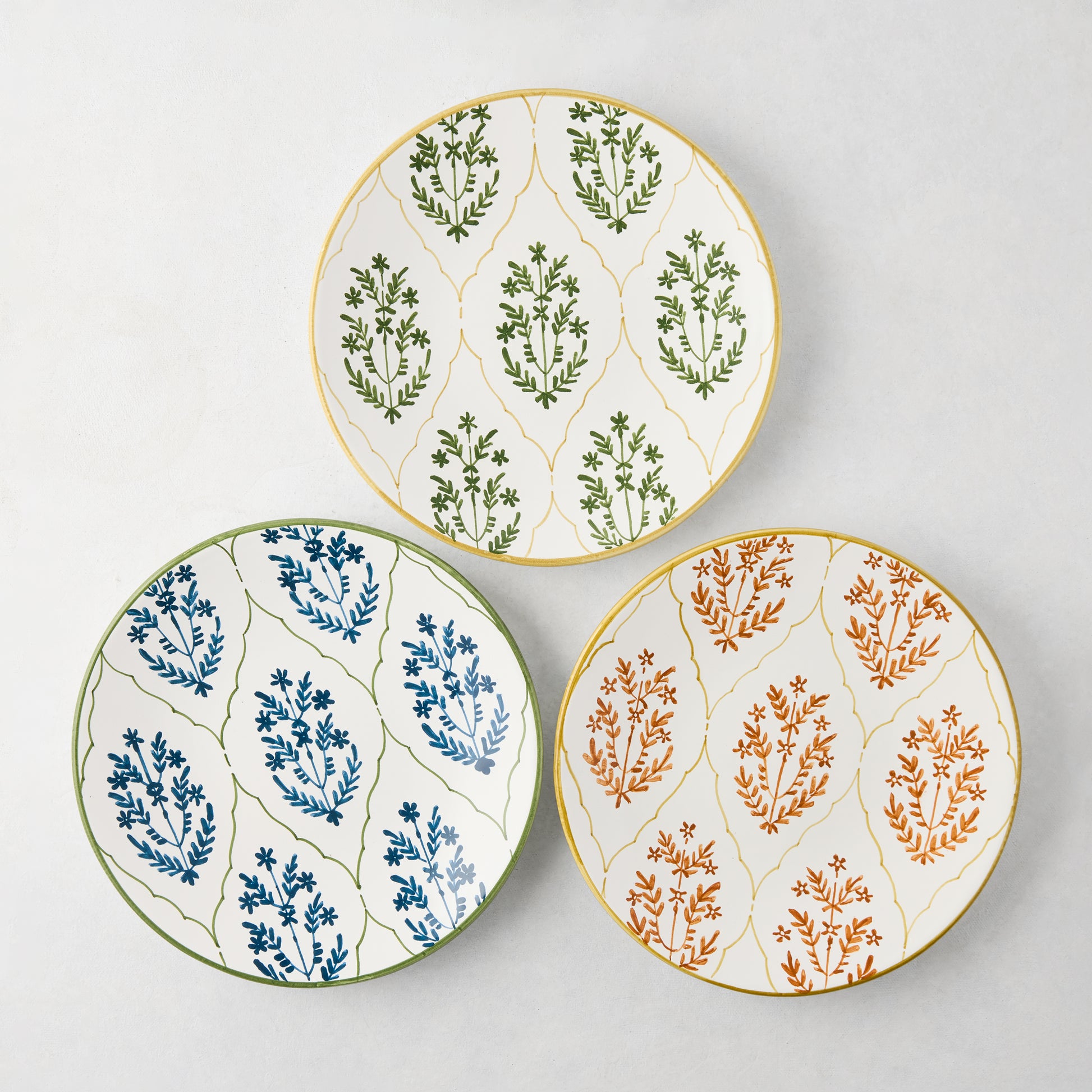Three Peter Dunham + Hudson Grace Jaali salad plates: olive green, blue, and terracotta floral patterns with yellow borders.