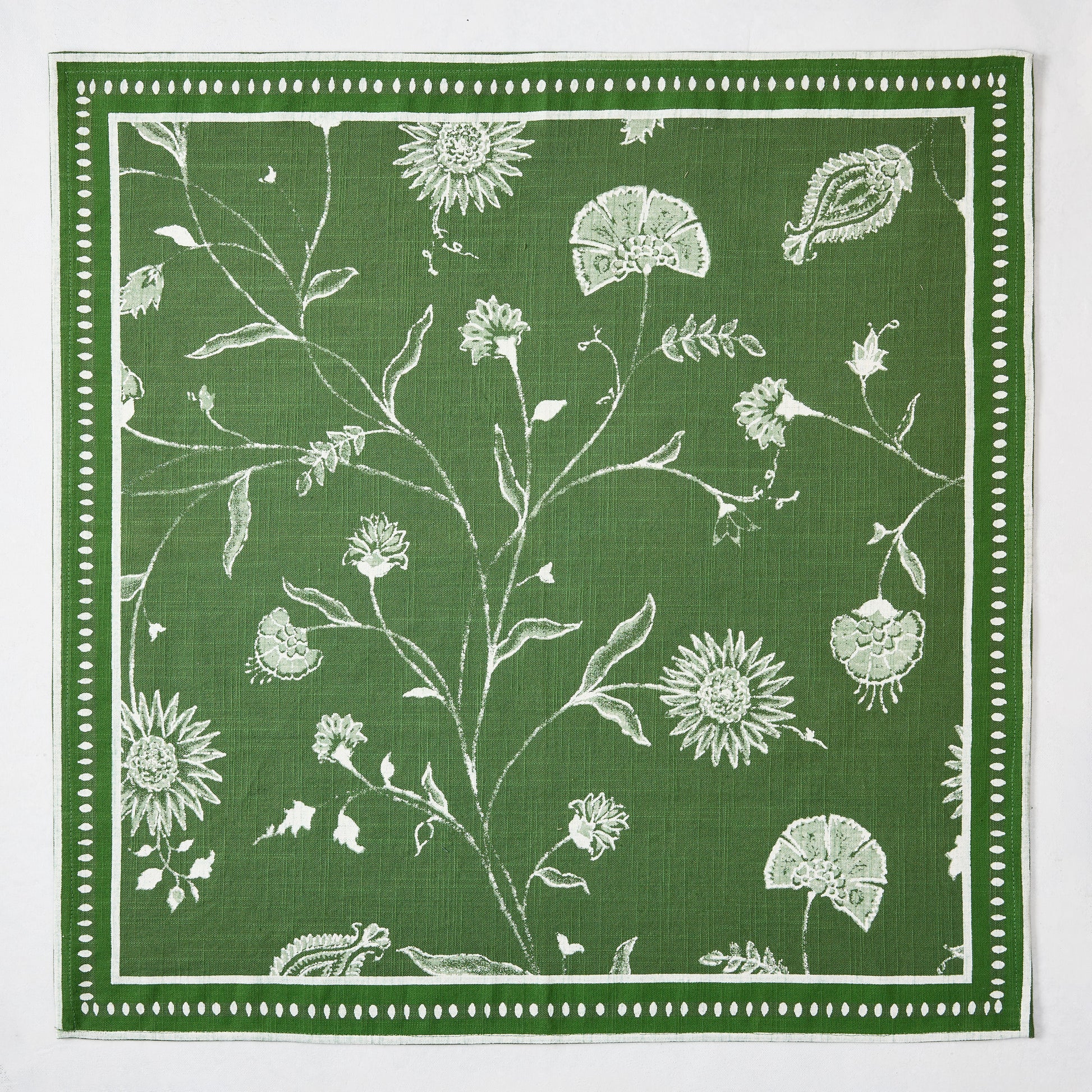Olive green Indian Chintz printed napkin with white rambling floral pattern and antique rug-inspired border.