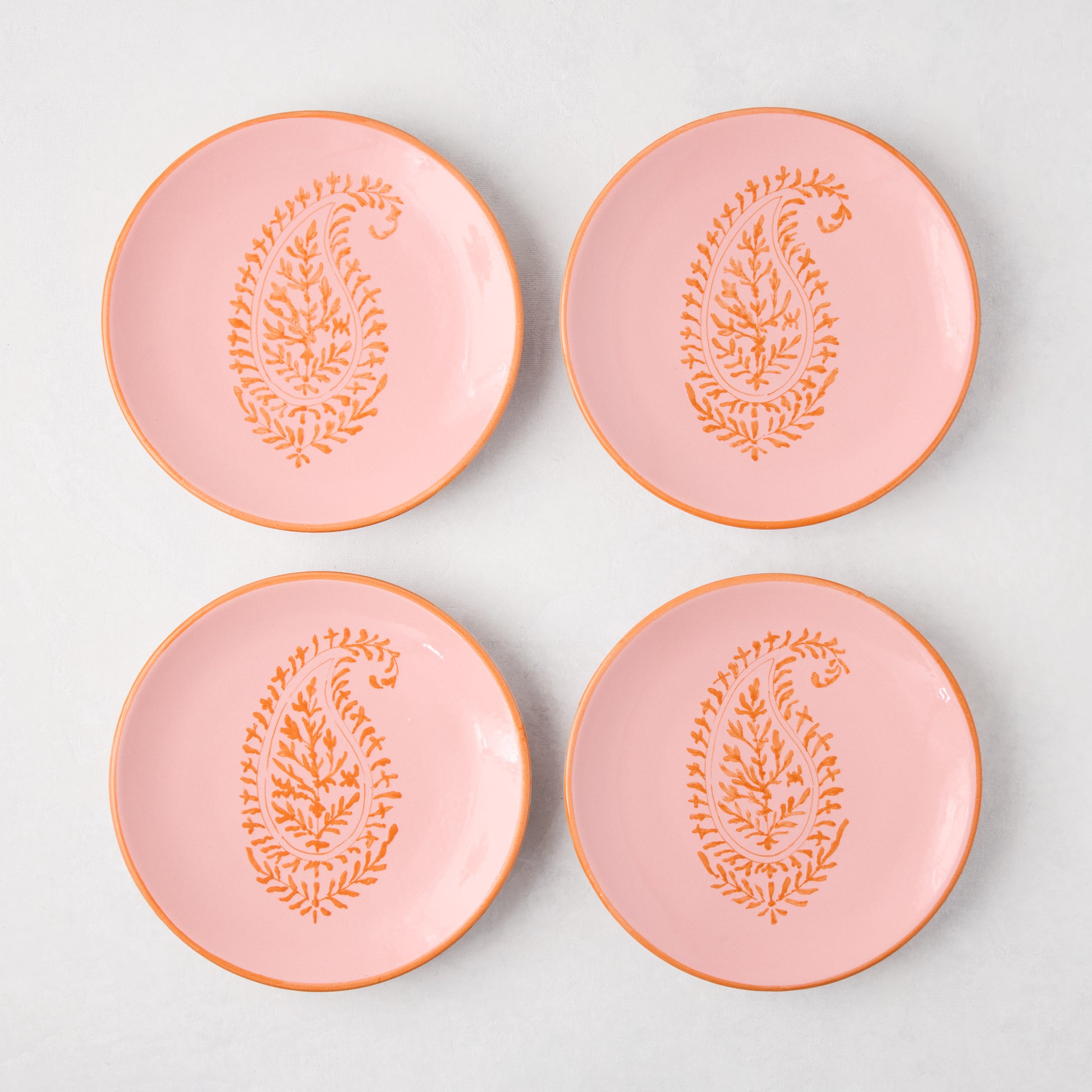 Four Peter Dunham + Hudson Grace pink hand-painted Kashmir Paisley appetizer plates with orange trim.