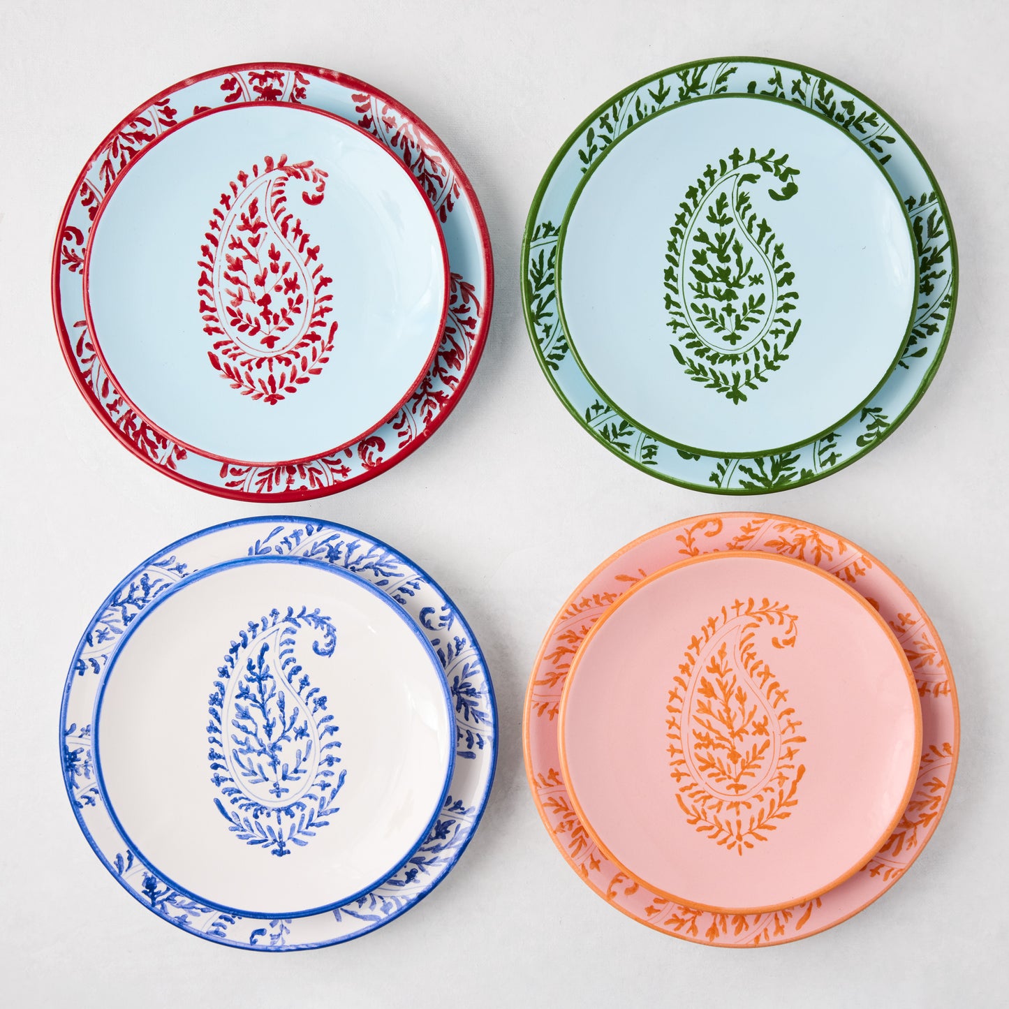 Four hand-painted Peter Dunham + Hudson Grace Kashmir Paisley appetizer plates in blue, green, white, and pink.