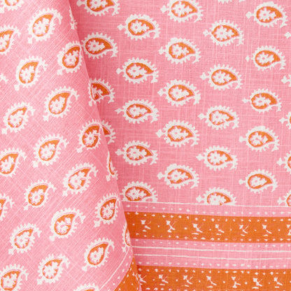 Pink cotton slub tablecloth with orange and white paisley floral print and graphic border detail.