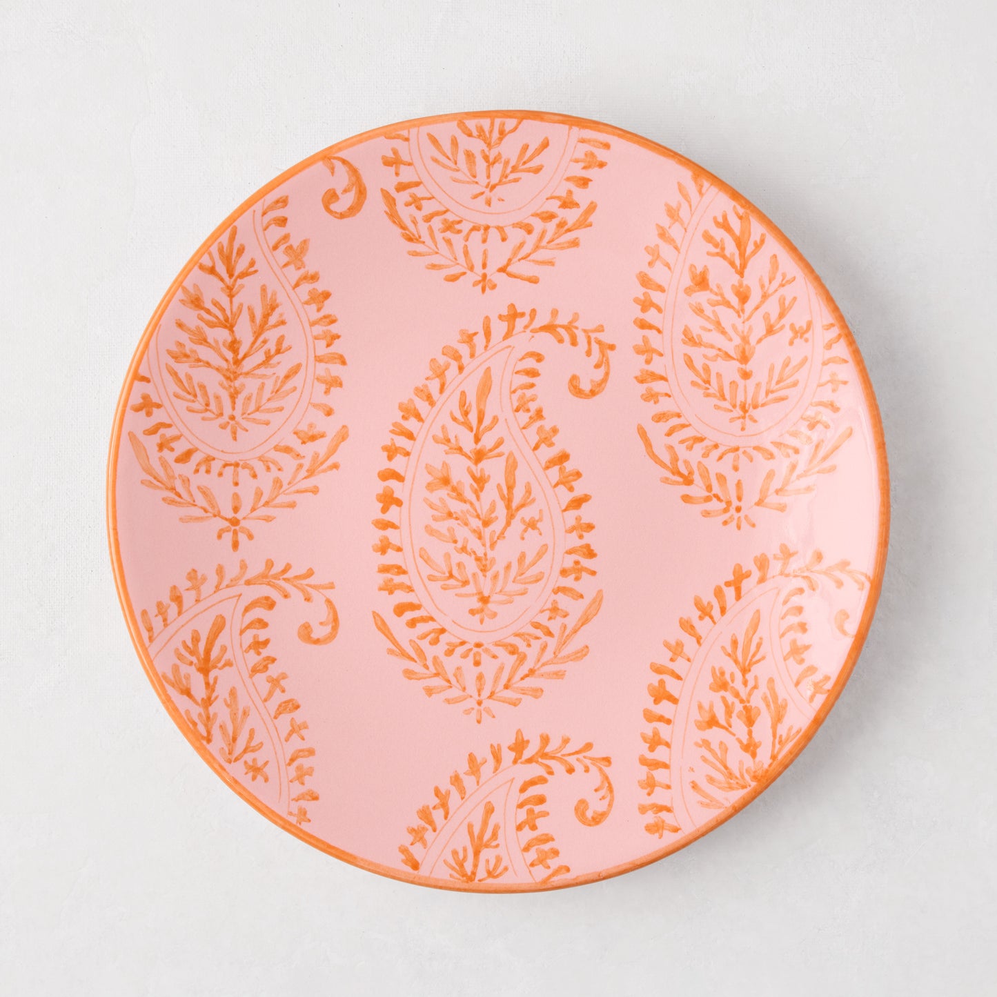 Pink Kashmir hand-painted paisley salad plate with orange design and rim.