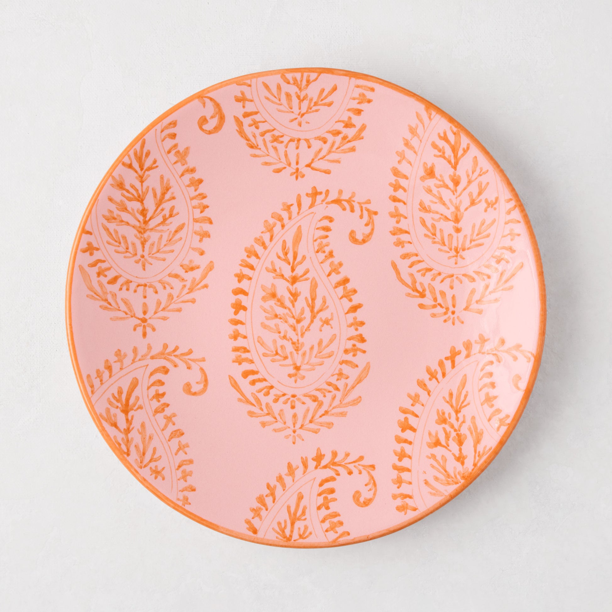 Pink Kashmir hand-painted paisley salad plate with orange design and rim.