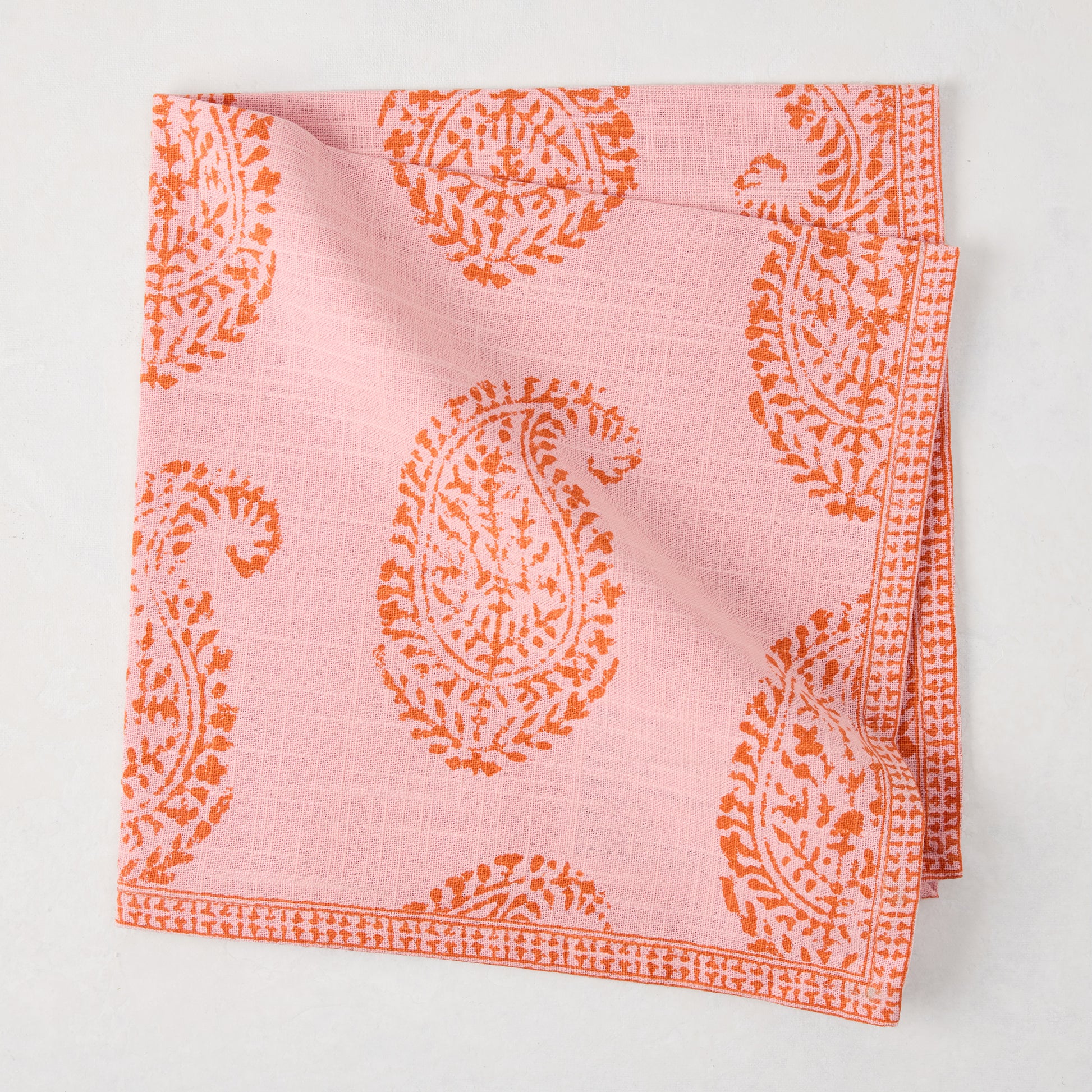 Pink Kashmir Paisley Printed Napkin by Peter Dunham + Hudson Grace, folded with orange paisley print.