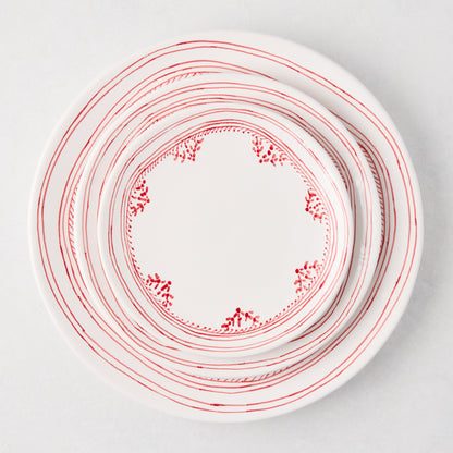 White ceramic appetizer plates with hand-painted red striped and dotted borders, stacked.