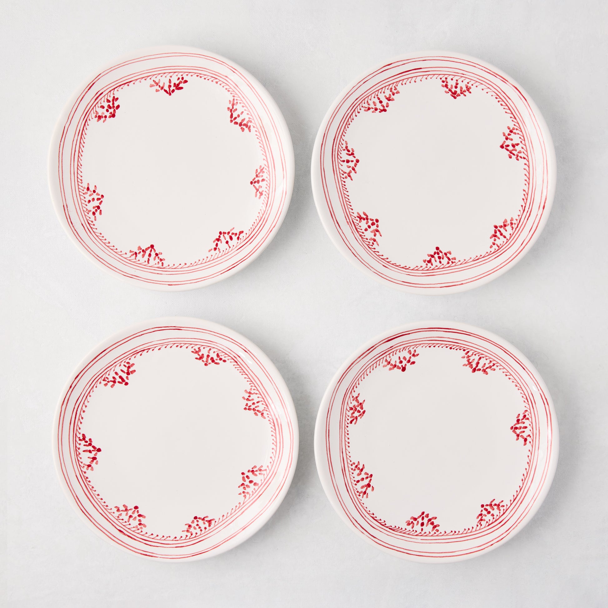 Four Peter Dunham + Hudson Grace Red Fez appetizer plates with hand-painted red borders.