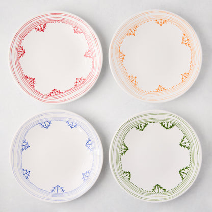 Four white Peter Dunham + Hudson Grace salad plates with hand-painted borders: red, orange, blue, and green.
