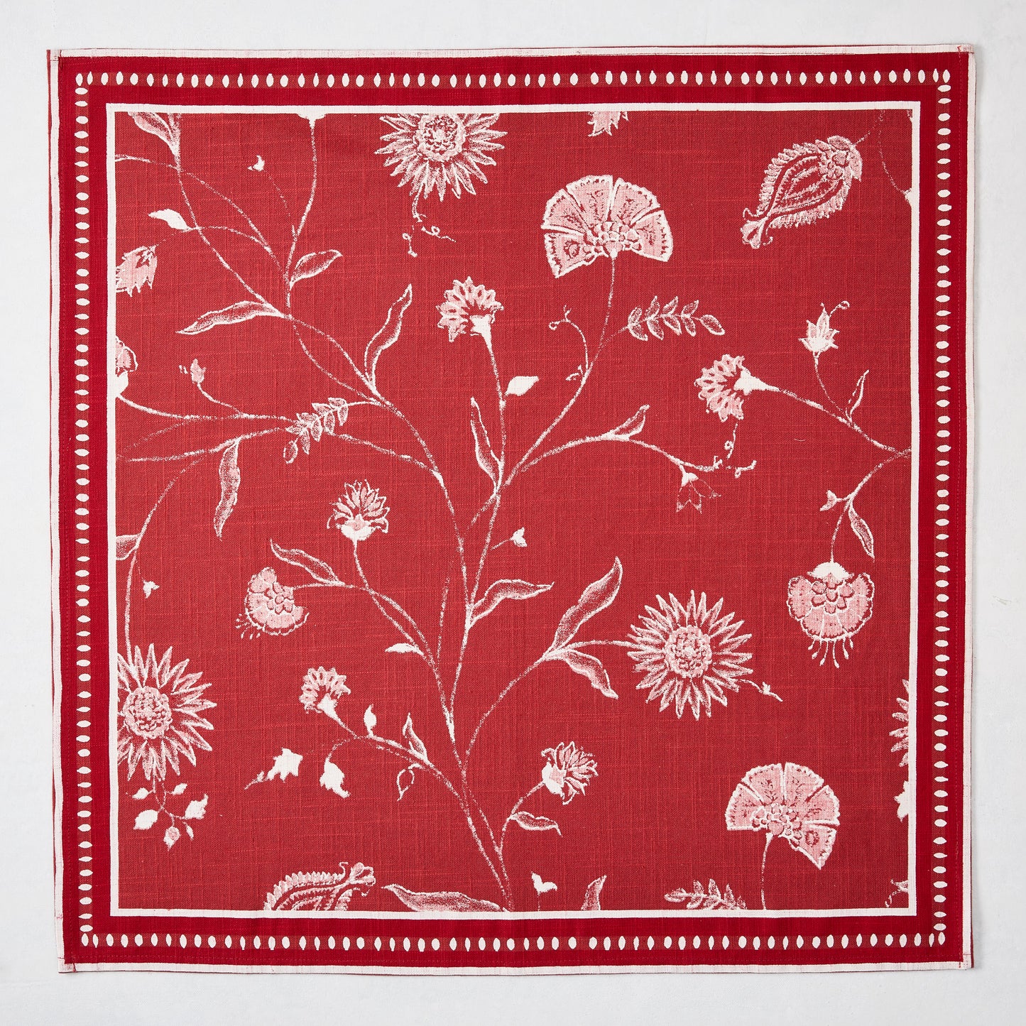 Red Indian Chintz cotton slub napkin with white floral pattern and dotted border.