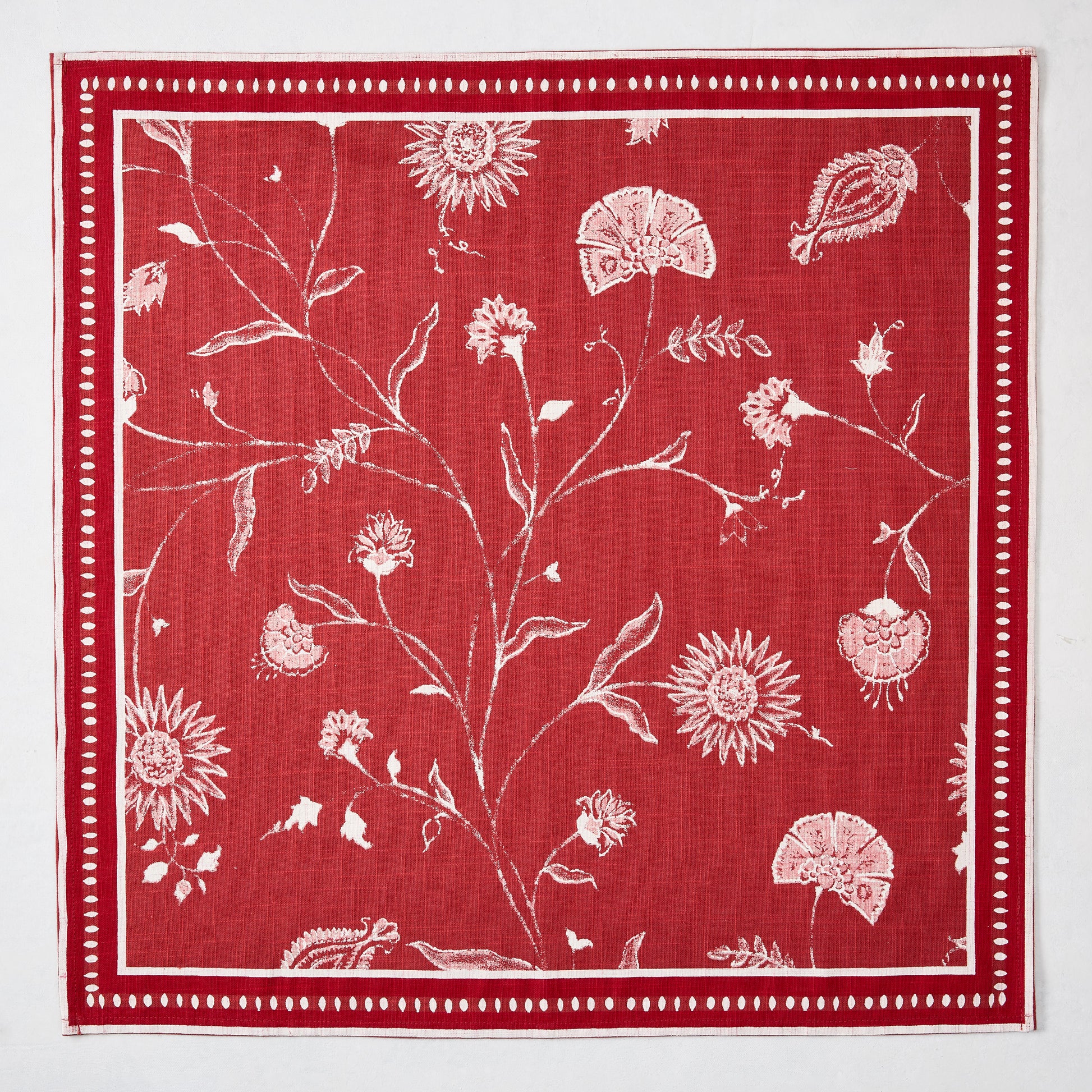 Red Indian Chintz cotton slub napkin with white floral pattern and dotted border.