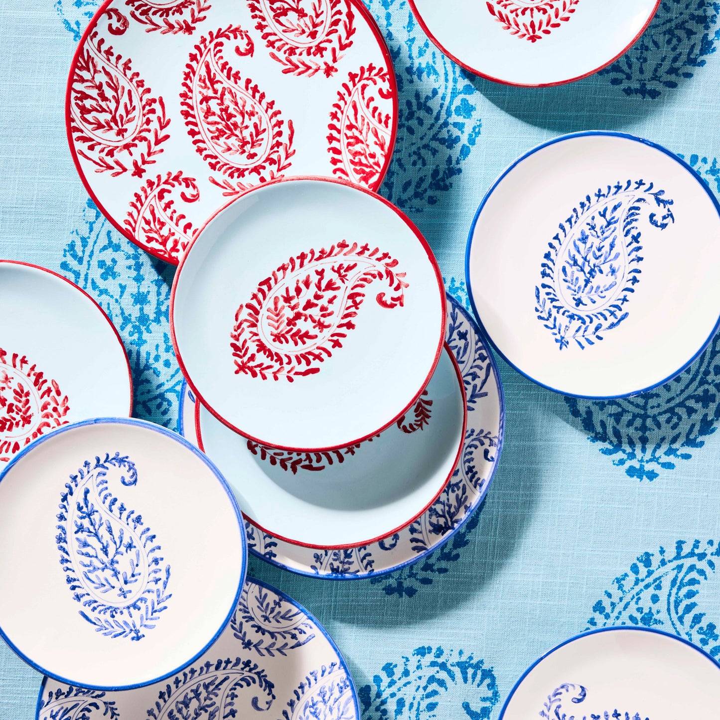 Peter Dunham + Hudson Grace hand-painted paisley salad plates in red and blue on a patterned tablecloth.
