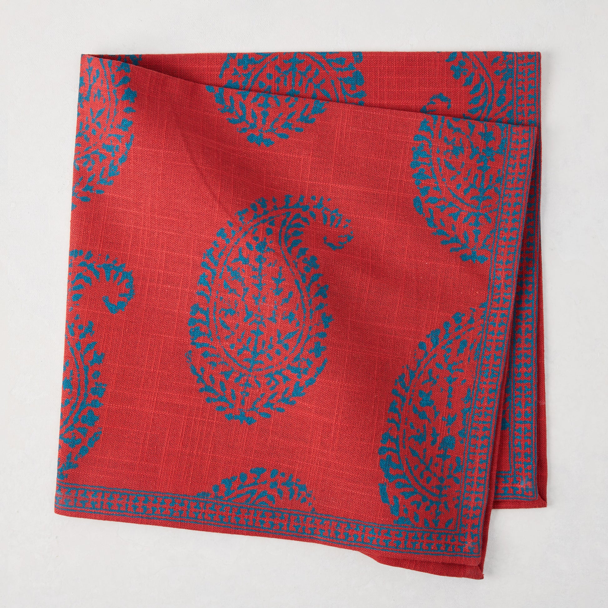 Red Kashmir Paisley Printed Napkin by Peter Dunham + Hudson Grace, folded with blue paisley pattern.