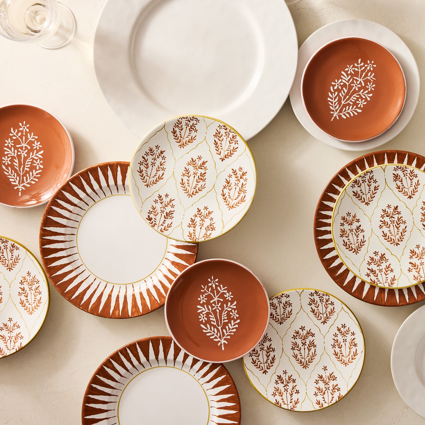 Peter Dunham + Hudson Grace Spice Orange Hand-Painted Sunburst Dinner Plate with ikat stripe and floral patterns.