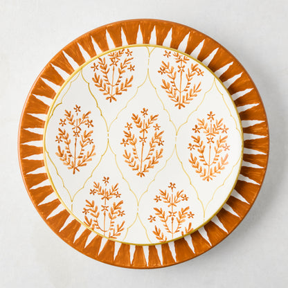 Peter Dunham + Hudson Grace Spice Orange Hand-Painted Sunburst Dinner Plate with a smaller floral patterned plate.