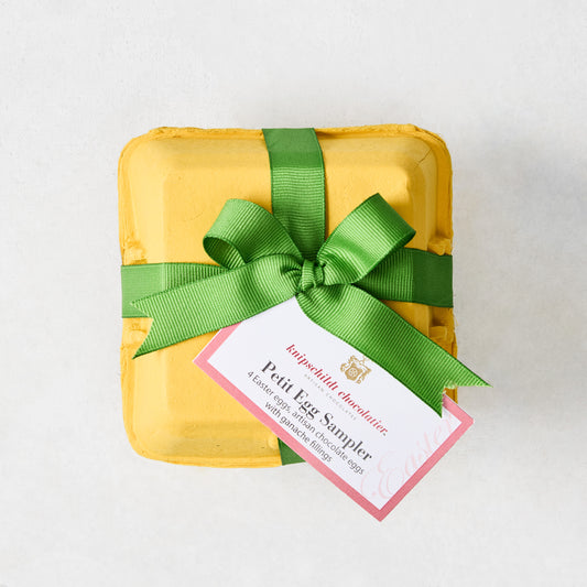 Yellow egg carton with green ribbon and "Petit Egg Sampler" tag.