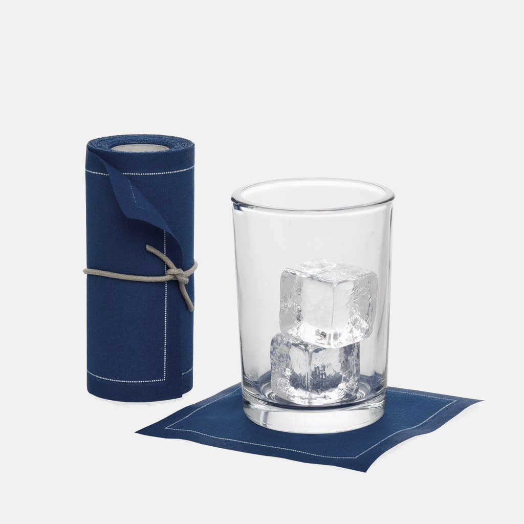 Petrol blue cotton tear-off cocktail napkins, roll of 50, with a glass and ice on one napkin.