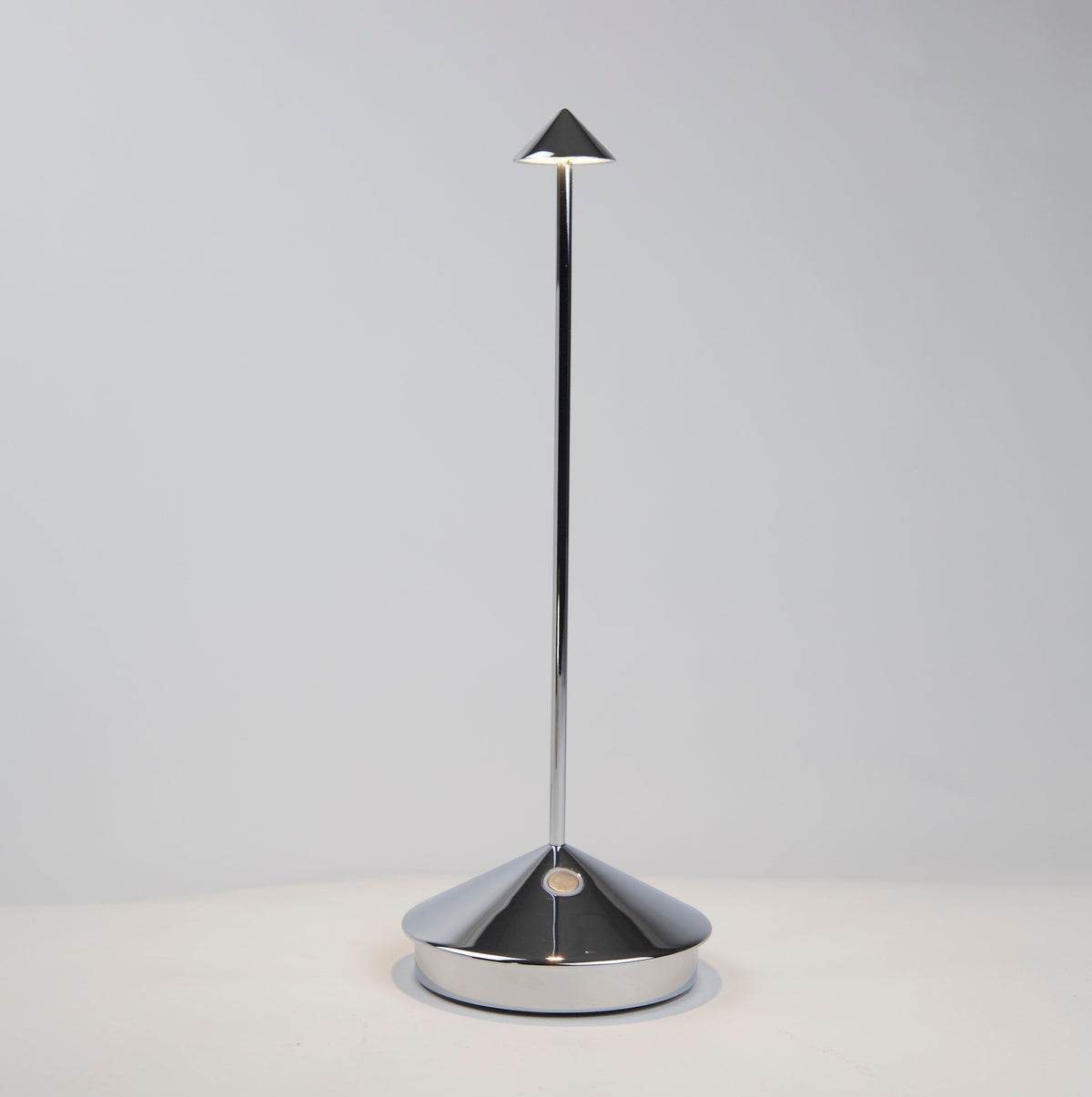 Pina Pro glossy chrome rechargeable LED lamp with a conical base and thin rod, emitting light from a small shade.