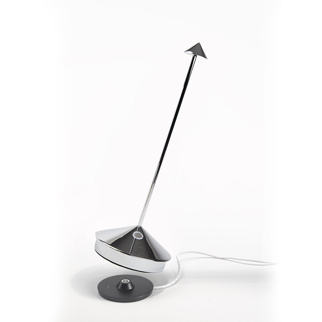 Pina Pro glossy chrome rechargeable LED lamp with broad base, thin rod, and small shade, next to charging base.