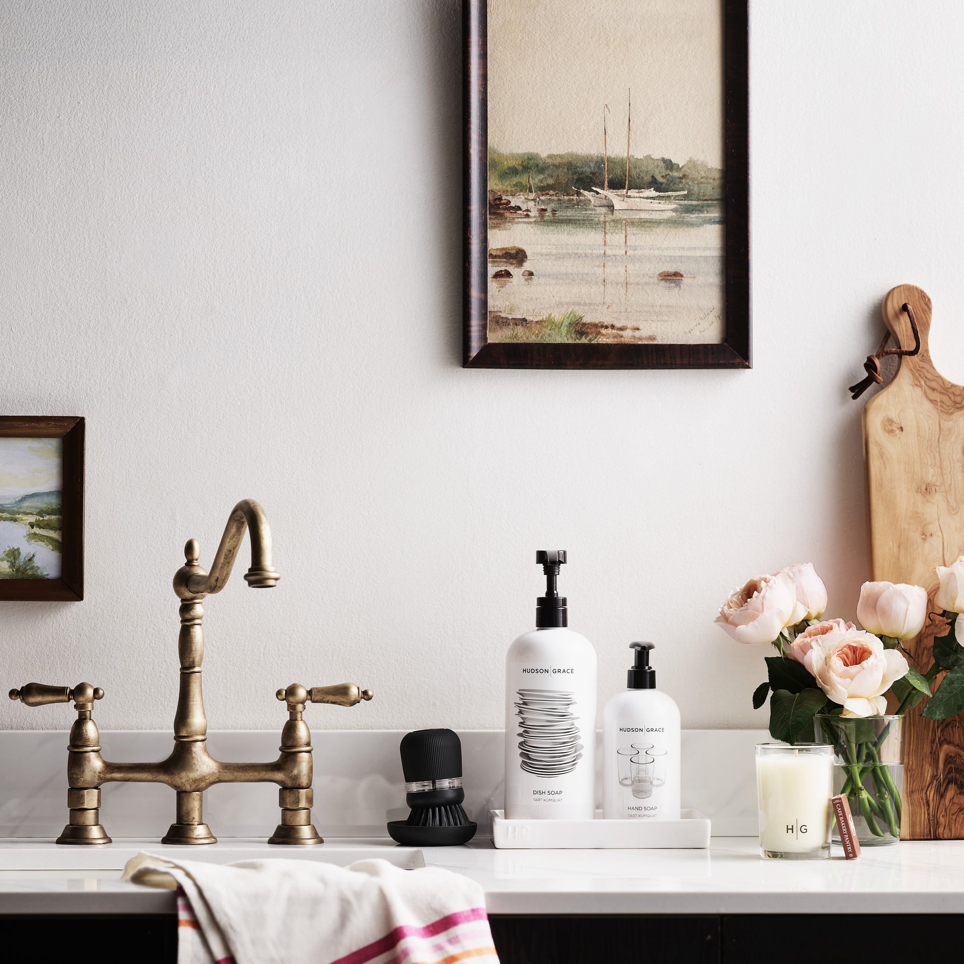 White hand towel with pink and orange triple stripes, draped over a kitchen counter.