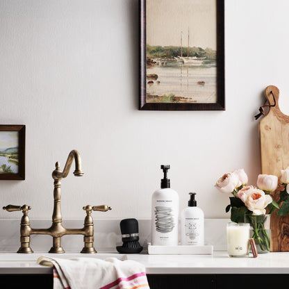 White hand towel with pink and orange triple stripes, draped over a kitchen counter.