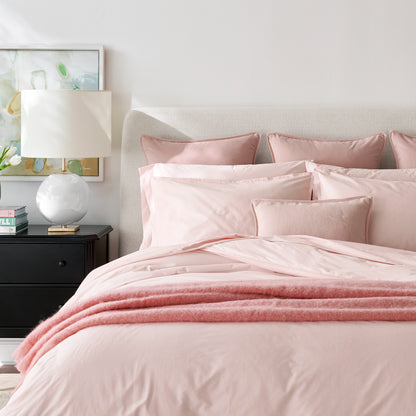 Pink linen and velvet reversible lumbar pillow on a bed with matching bedding.