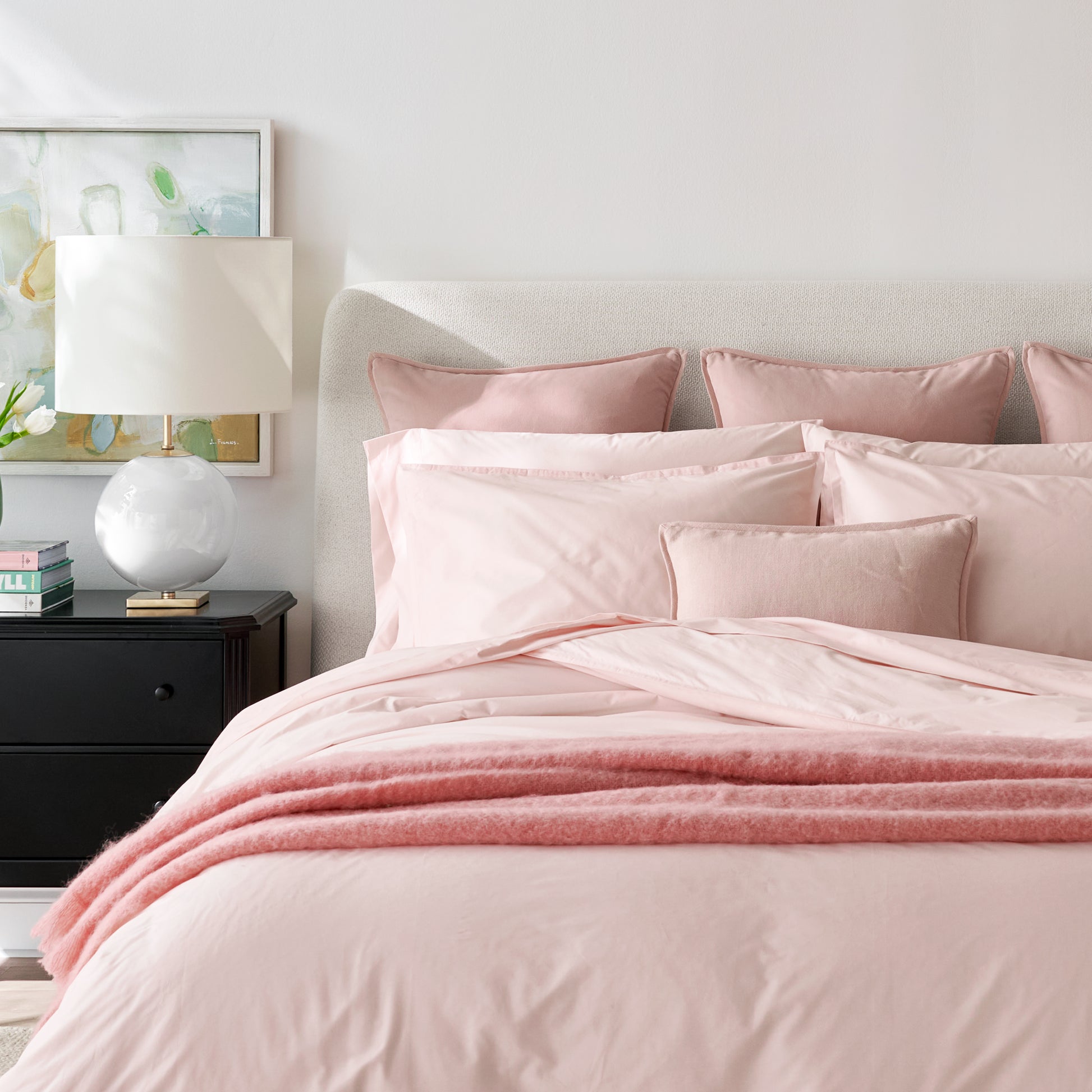 Pink linen and velvet square reversible pillow on a bed with matching bedding.