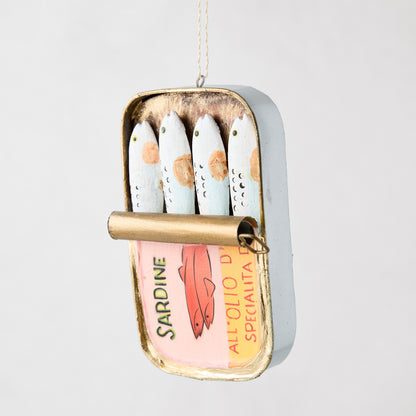 Hand-painted glass and resin sardine tin ornament with pink label and four small fish, hanging by a string.
