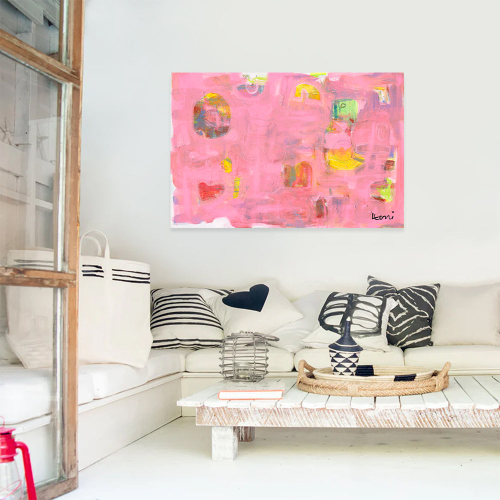 Pinkaholic abstract art print by Kerri Rosenthal, featuring vibrant pinks, yellows, and heart shapes, displayed above a white sofa.