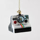 Hand-painted glass and resin Polaroid camera ornament with glitter accents and a rainbow stripe detail.
