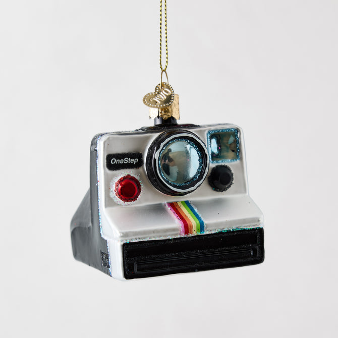Hand-painted glass and resin Polaroid camera ornament with glitter accents and a rainbow stripe detail.