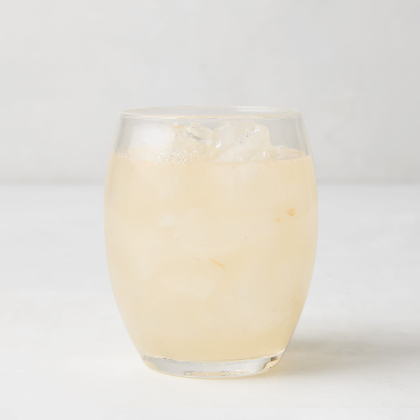 Clear 18oz Poolside Acrylic Stemless Wine Glass filled with a light-colored drink and ice.