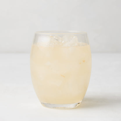 Clear 18oz Poolside Acrylic Stemless Wine Glass filled with a light-colored drink and ice.