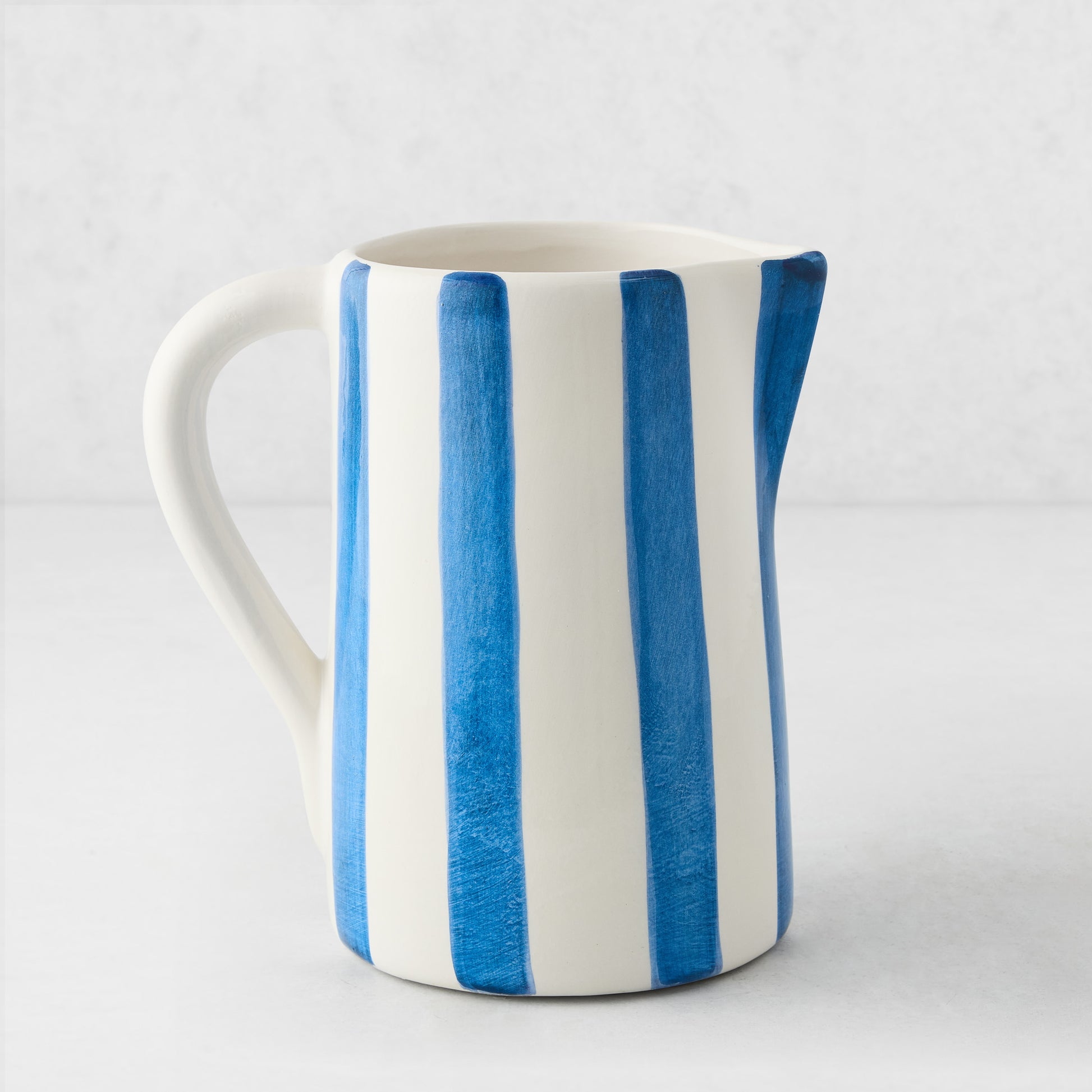 Portofino Blue Stripe Medium Ceramic Pitcher, white with hand-painted blue vertical stripes, curved handle and spout.