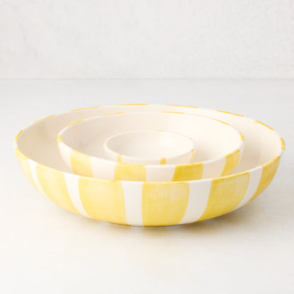 Three nested Portofino ceramic serve bowls with hand-painted yellow stripes.