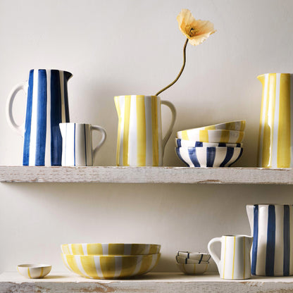 Small Portofino ceramic pitcher with hand-painted thin yellow stripes, curved handle, and spout.