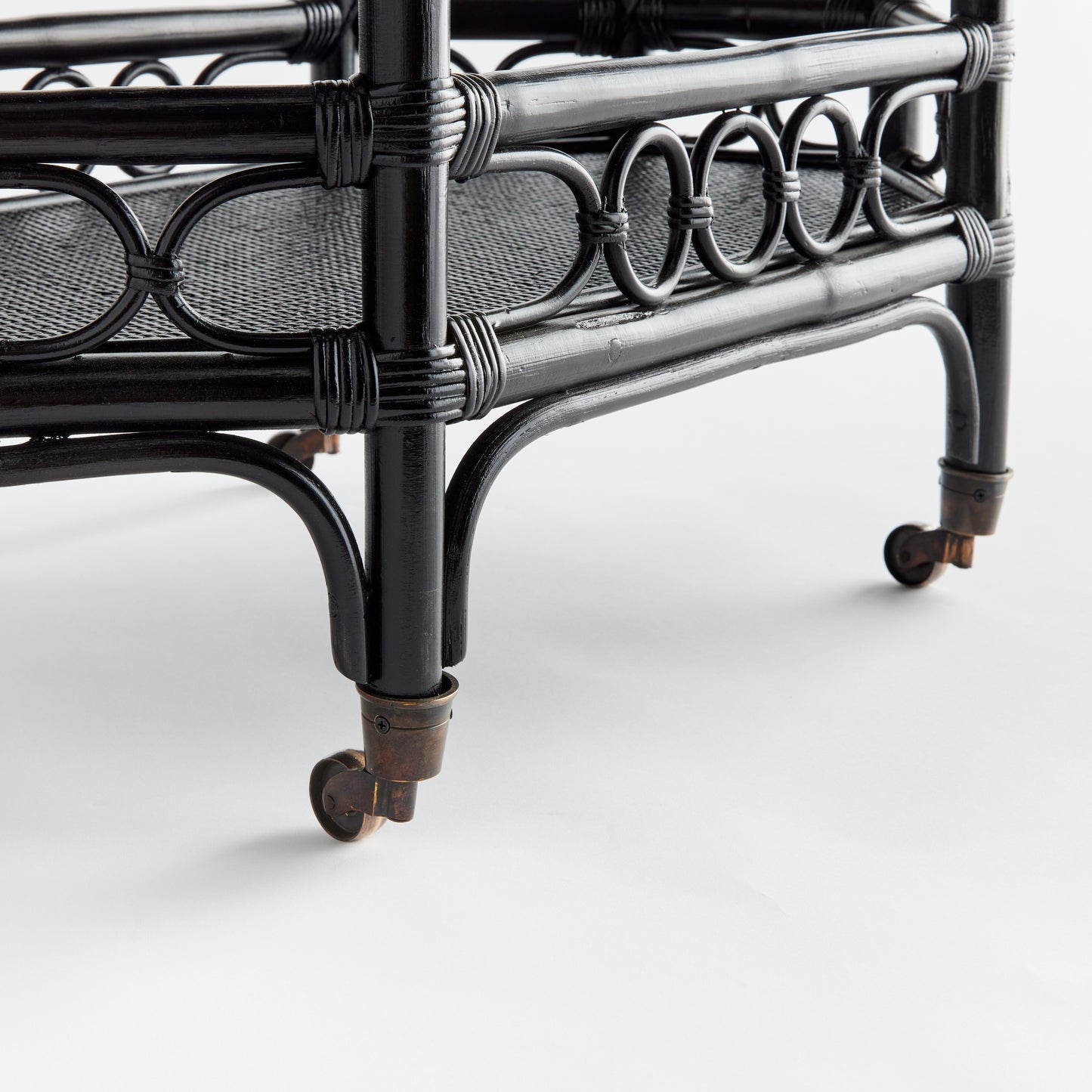 Raelyn black rattan bar cart with dark wood shelves and smooth-rolling casters.