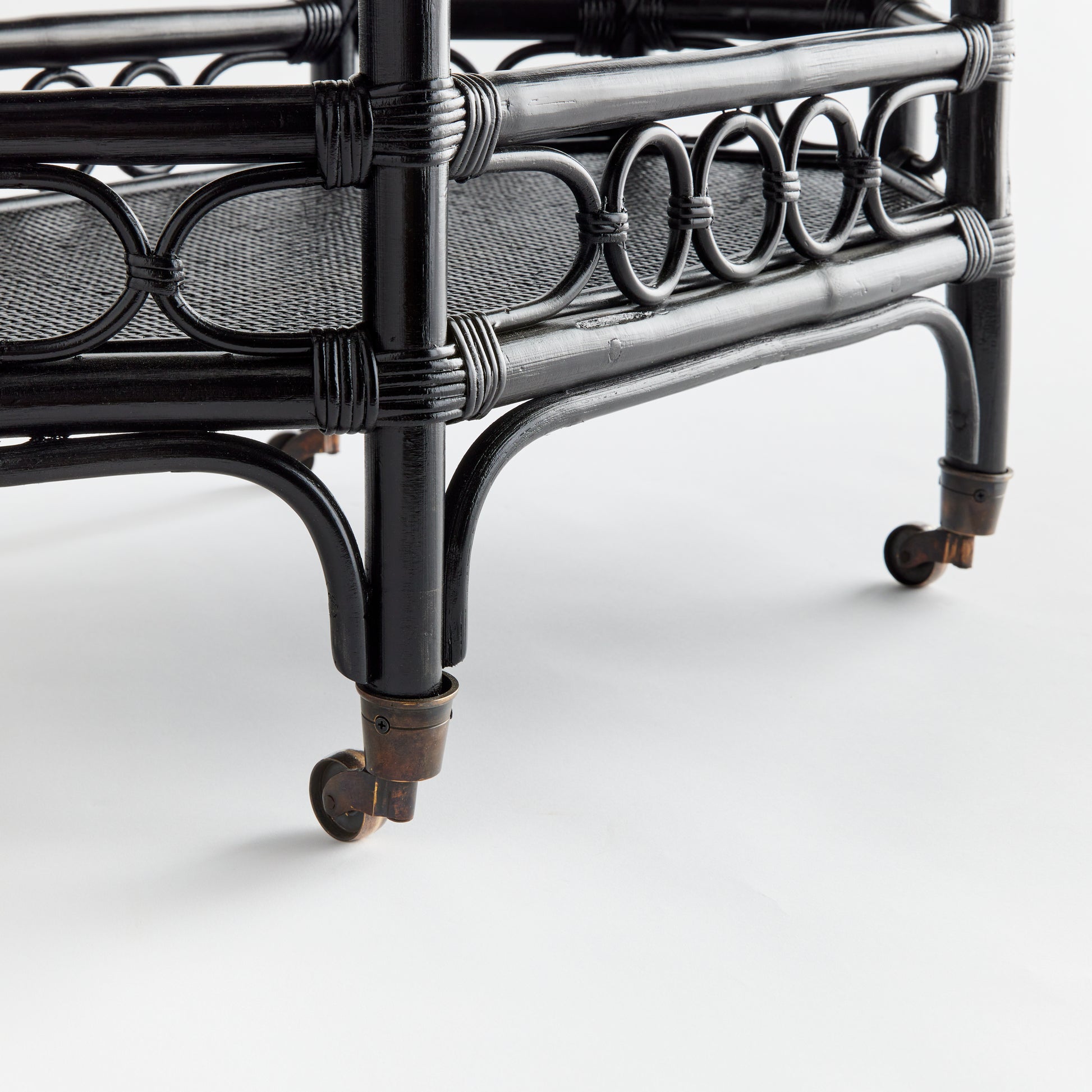 Raelyn black rattan bar cart with dark wood shelves and smooth-rolling casters.