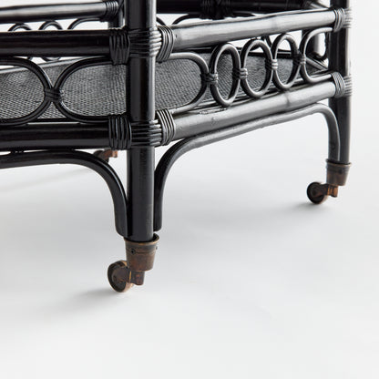 Raelyn black rattan bar cart with dark wood shelves and smooth-rolling casters.