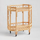 Natural Raelyn Bar Cart with two dark wood shelves, handmade rattan frame, and rolling casters.