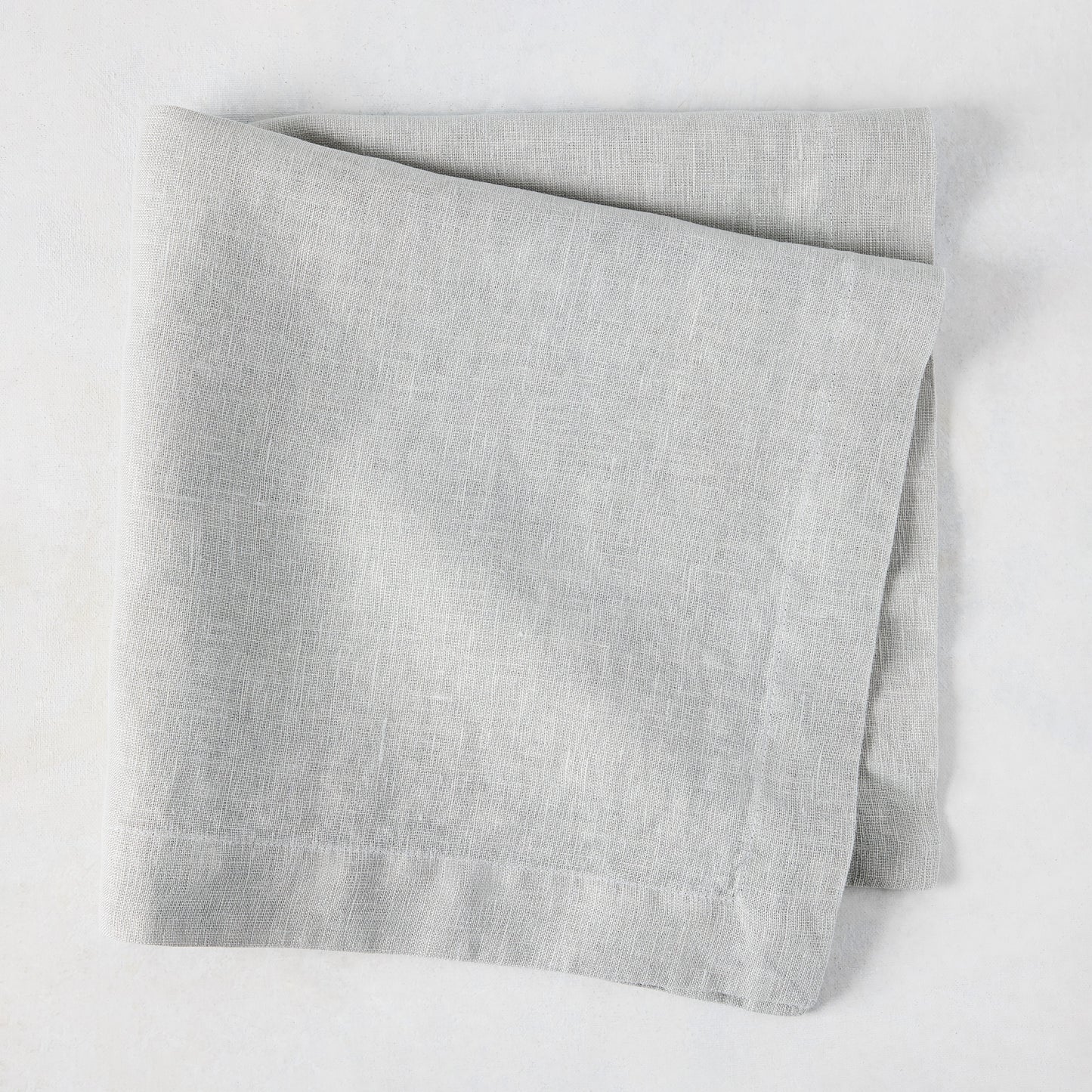Rain HG Signature hand-dyed light grey linen napkin, 22-inch square, folded.