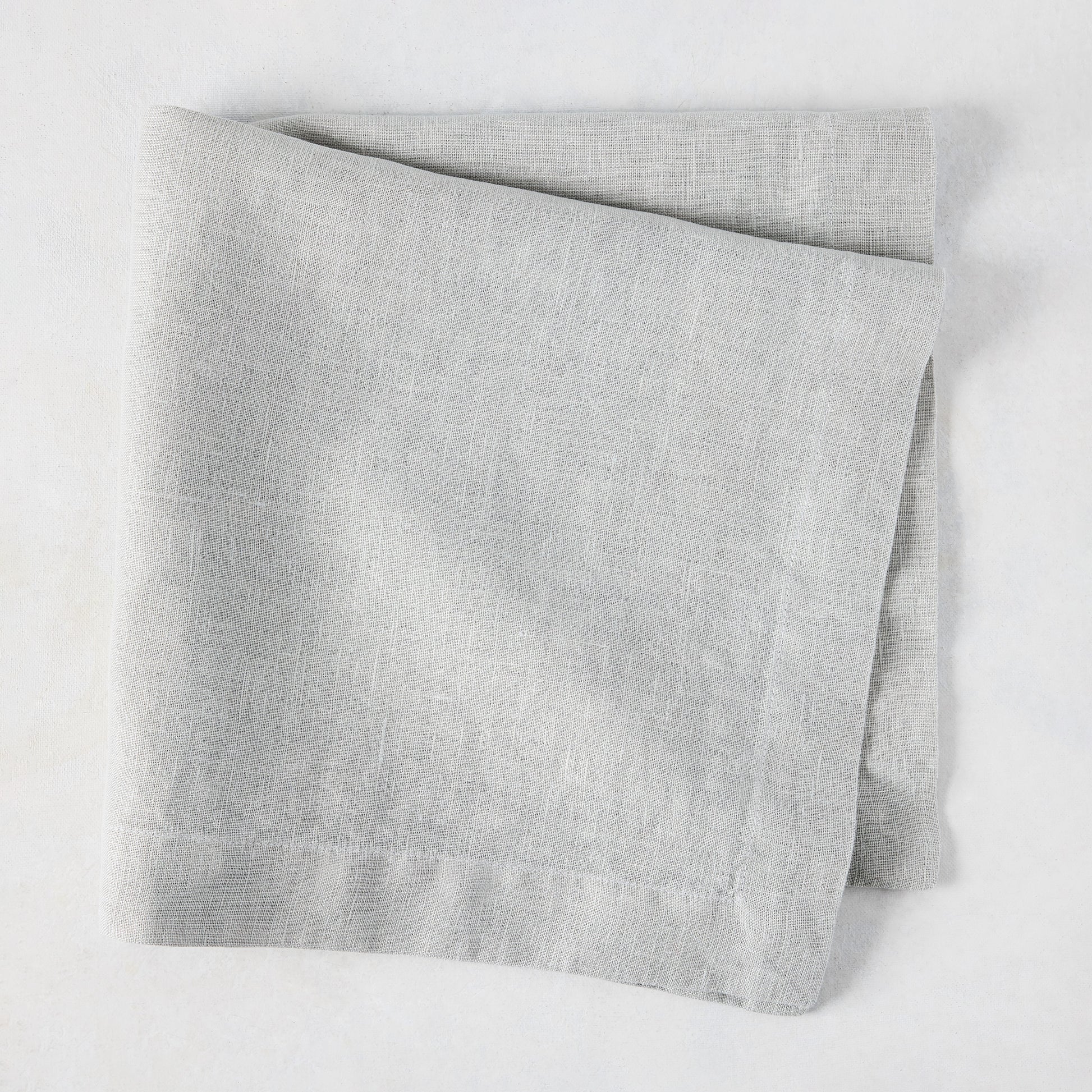 Rain HG Signature hand-dyed light grey linen napkin, 22-inch square, folded.