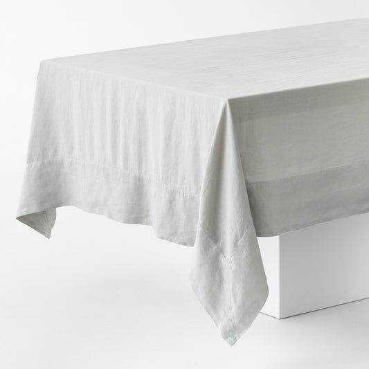Light grey hand-dyed 100% linen tablecloth with mitered corner detailing on a white table.