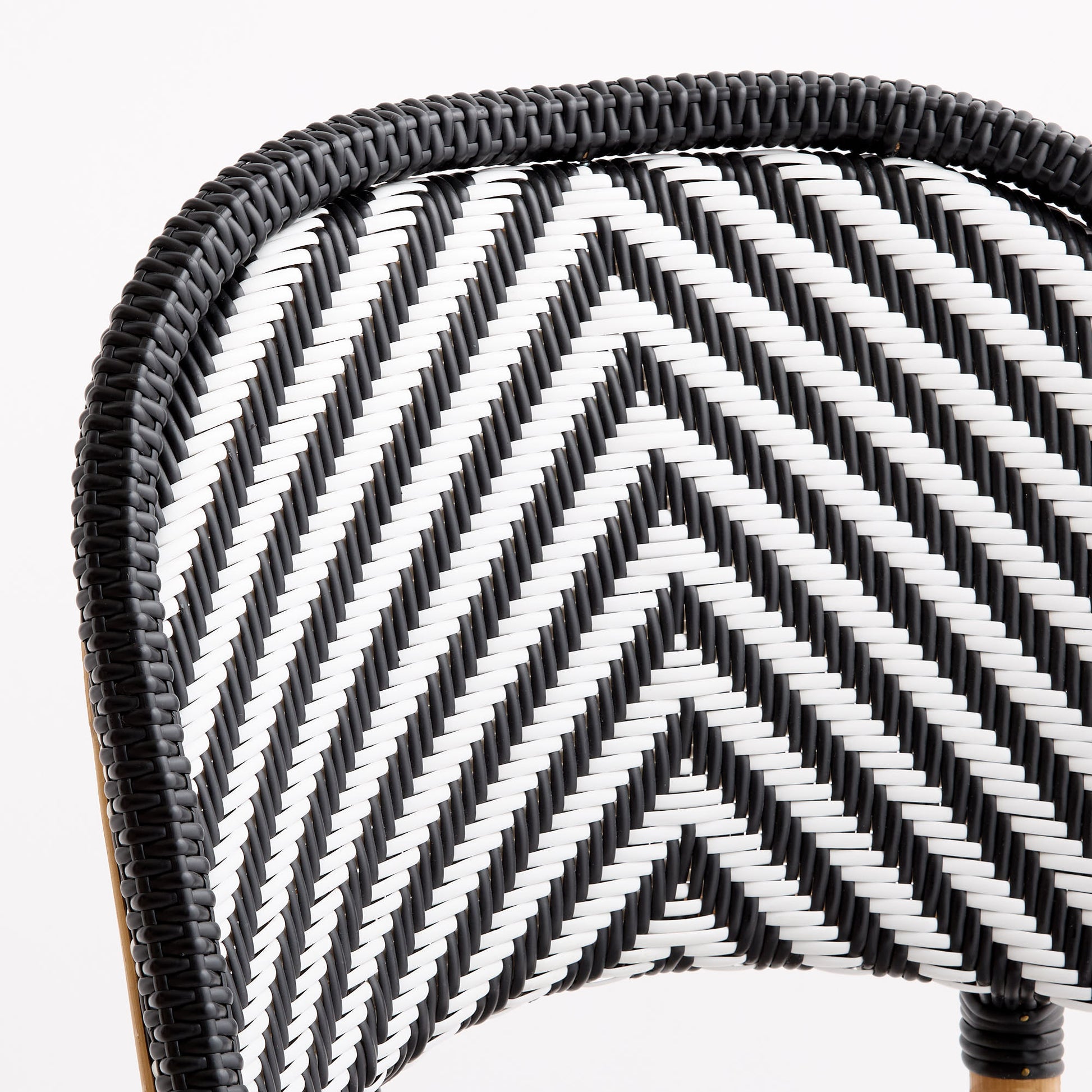 Black and white woven rattan bistro chair back with a chevron pattern and solid black border.
