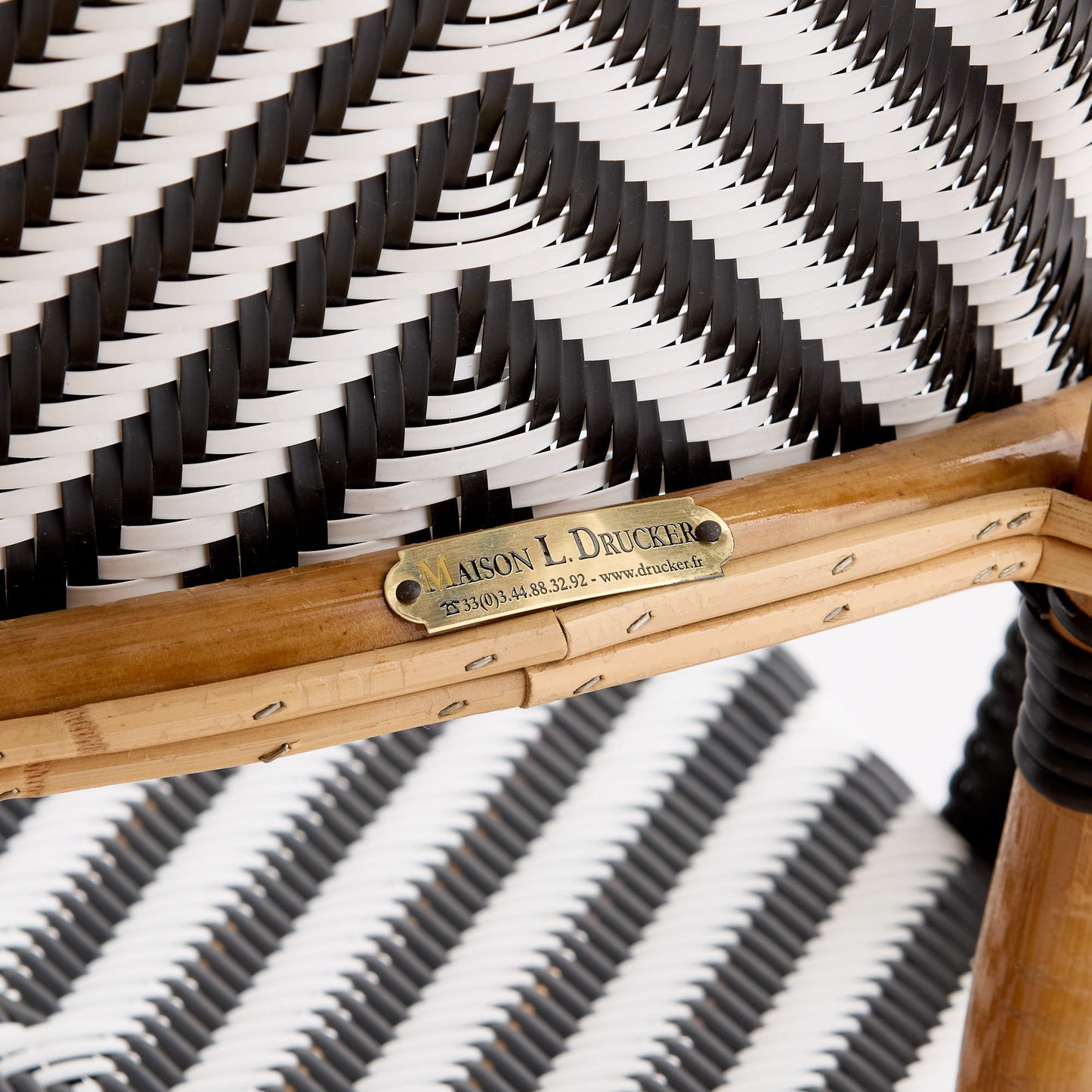 Maison Drucker rattan bistro chair with black and white chevron woven pattern and brass manufacturer nameplate.