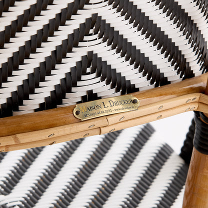 Maison Drucker rattan bistro chair with black and white chevron woven pattern and brass manufacturer nameplate.